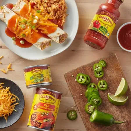 A plate of burritos on a wood table with Old El Paso sauces and various other ingredients 